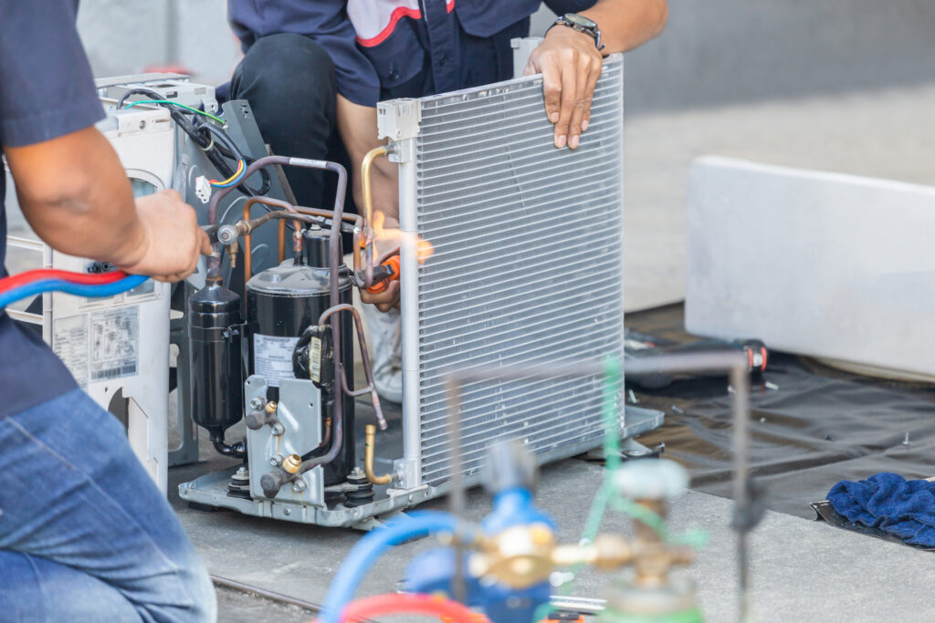 Close up of an AC repair team using fuel gases and oxygen to weld or cut metals